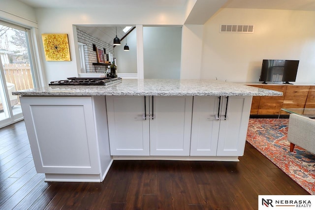 kitchen featuring dark wood-style flooring, visible vents, and light stone countertops