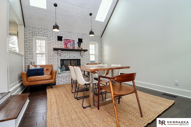 dining area with a skylight, visible vents, baseboards, a brick fireplace, and wood-type flooring