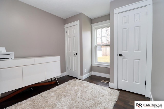 unfurnished bedroom featuring dark wood-type flooring, visible vents, and baseboards