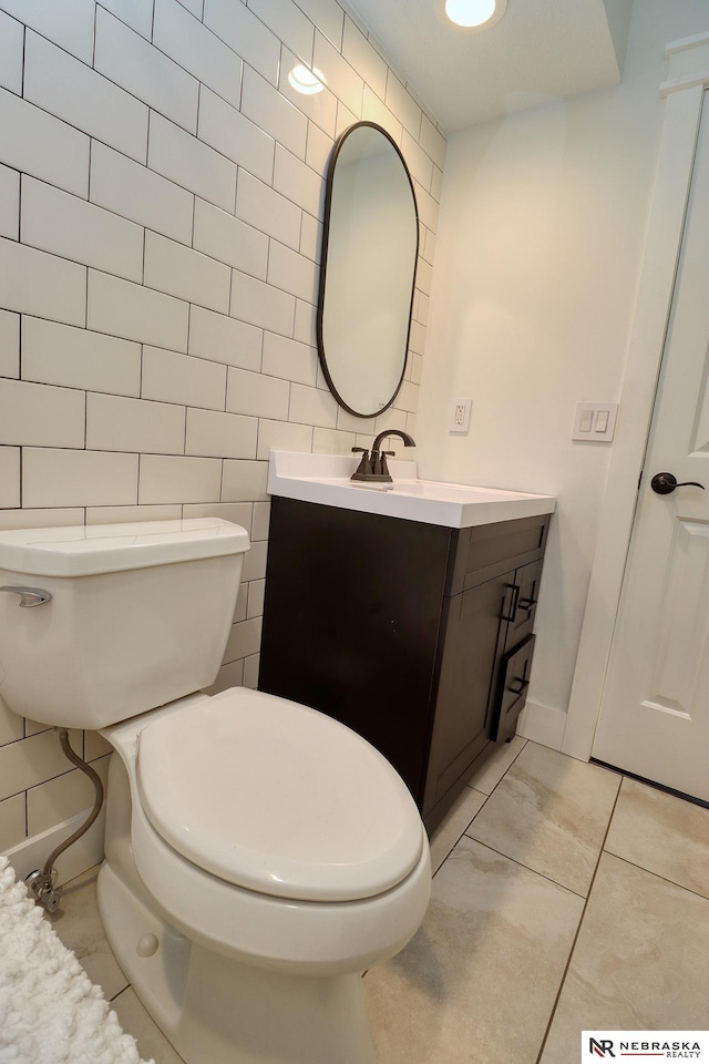 half bath with vanity, toilet, and tile walls