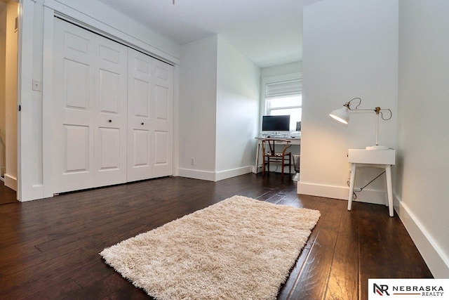 bedroom featuring dark wood-style floors, baseboards, and a closet