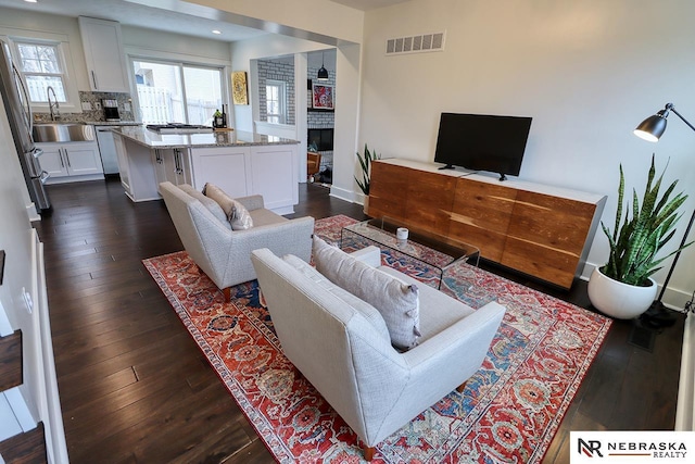 living area featuring baseboards, visible vents, dark wood finished floors, a fireplace, and recessed lighting