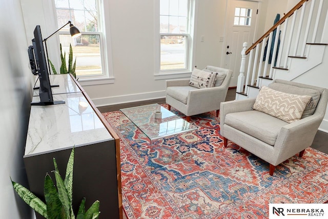 living area featuring stairs, baseboards, and wood finished floors