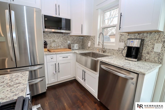 kitchen featuring white cabinets, appliances with stainless steel finishes, backsplash, and a sink