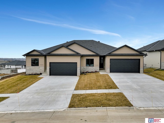 view of front of home with a front lawn, concrete driveway, stone siding, and an attached garage