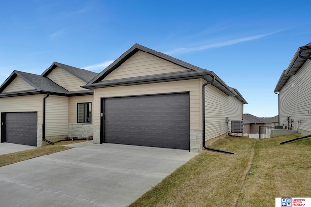 view of front of property featuring an attached garage, cooling unit, concrete driveway, and a front yard