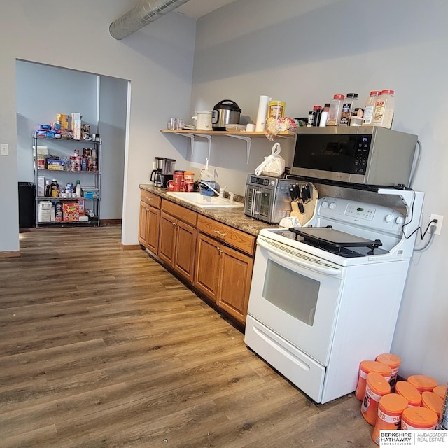 kitchen with a sink, brown cabinets, open shelves, stainless steel microwave, and white electric range oven