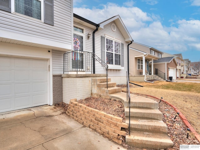 split level home with a garage, concrete driveway, and brick siding