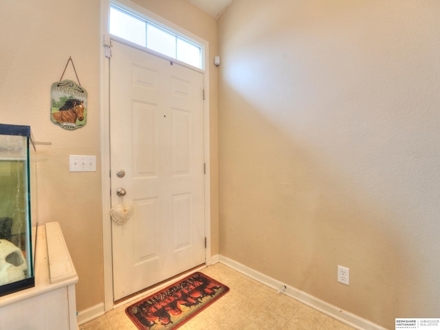 foyer entrance with light floors and baseboards