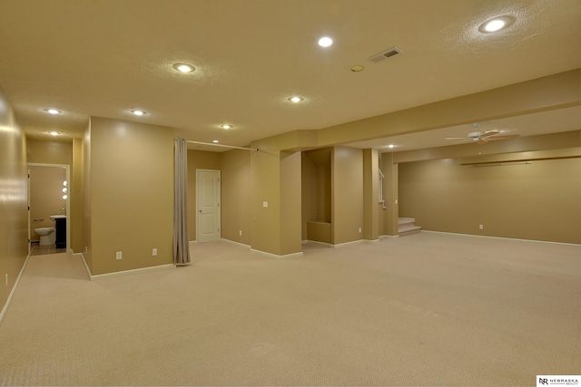 finished basement with visible vents, light colored carpet, stairs, a textured ceiling, and recessed lighting