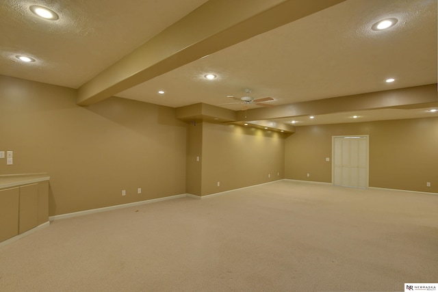 finished below grade area with a textured ceiling, baseboards, light carpet, and recessed lighting