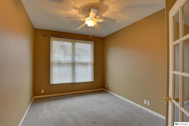 spare room with carpet, baseboards, a ceiling fan, and french doors