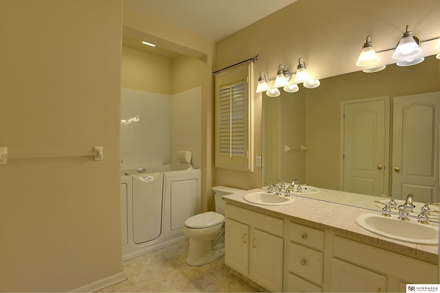 bathroom with double vanity, independent washer and dryer, a sink, and a tub