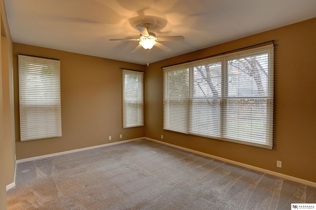 empty room featuring carpet, baseboards, and a ceiling fan