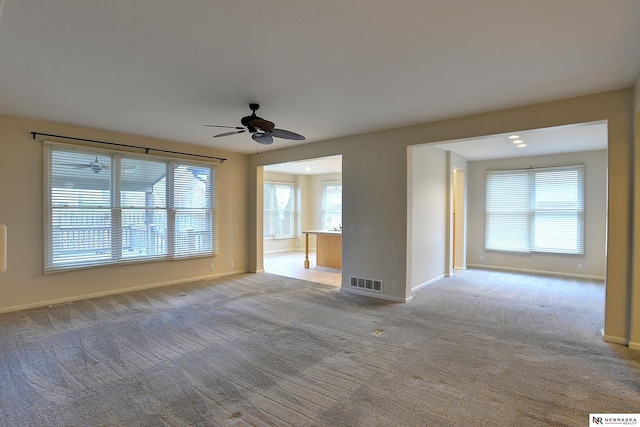 unfurnished living room featuring a ceiling fan, carpet, visible vents, and baseboards