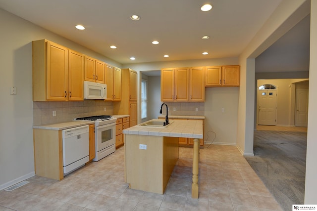 kitchen featuring tile countertops, a kitchen island with sink, white appliances, a sink, and visible vents