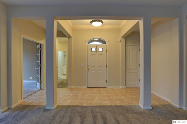 foyer with light carpet, light tile patterned floors, and baseboards