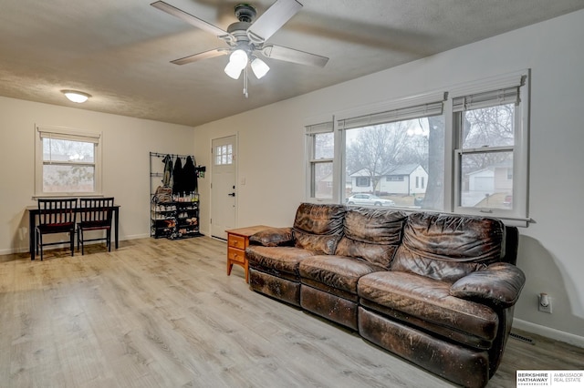 living room with a ceiling fan, baseboards, and wood finished floors