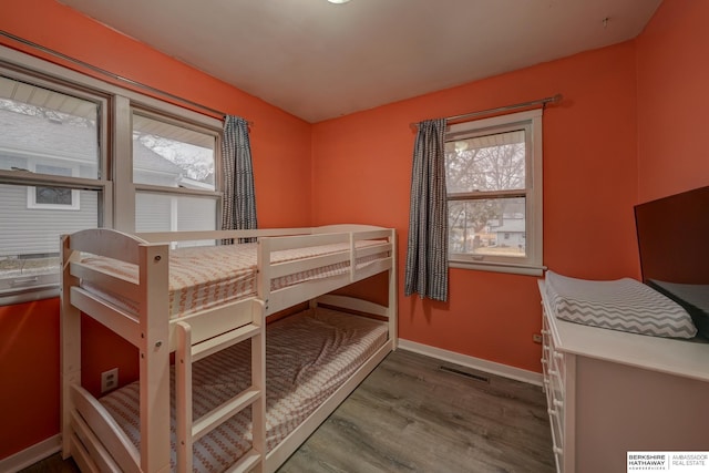 bedroom with visible vents, baseboards, and wood finished floors