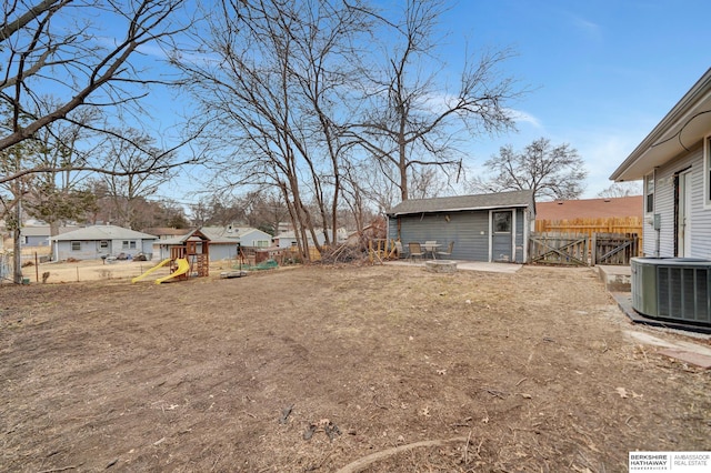 view of yard featuring an outbuilding, a playground, central air condition unit, a gate, and fence