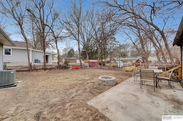 view of yard with an outdoor fire pit, fence, outdoor dining area, central air condition unit, and a patio area