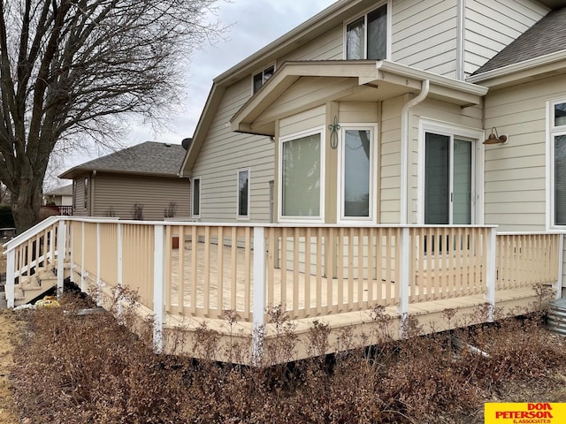 view of side of property featuring a deck and roof with shingles