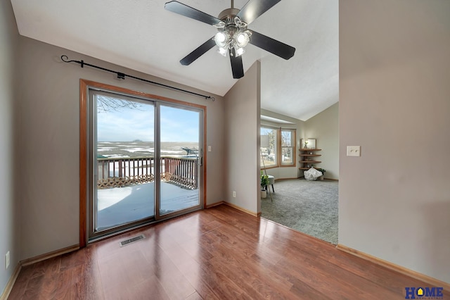 empty room with lofted ceiling, wood finished floors, visible vents, and baseboards