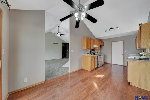 kitchen featuring lofted ceiling, light countertops, light wood-style floors, stainless steel range with electric stovetop, and under cabinet range hood