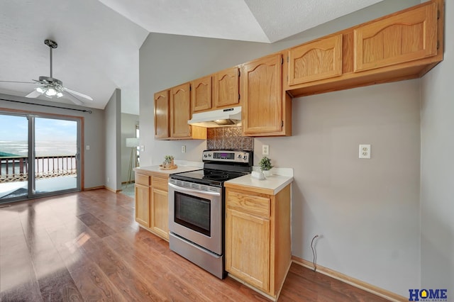 kitchen with electric stove, light countertops, vaulted ceiling, light wood-type flooring, and under cabinet range hood