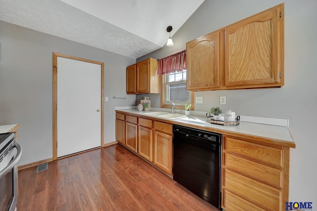 kitchen featuring lofted ceiling, wood finished floors, a sink, black dishwasher, and light countertops