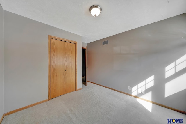 unfurnished bedroom with carpet, a closet, visible vents, and baseboards