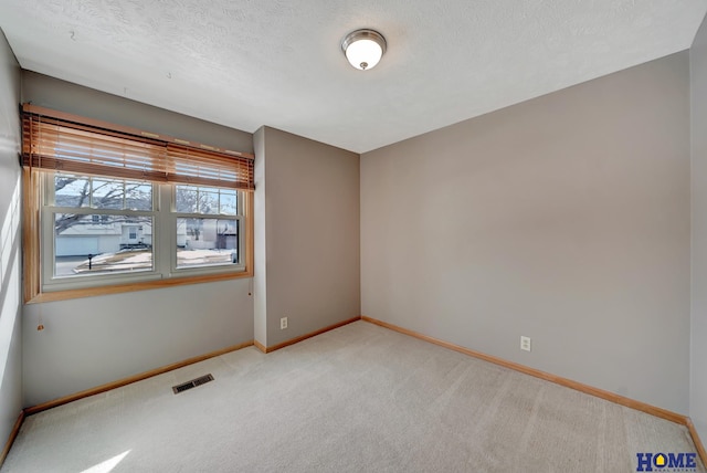 spare room featuring light carpet, baseboards, visible vents, and a textured ceiling