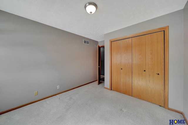 unfurnished bedroom featuring baseboards, a closet, visible vents, and light colored carpet