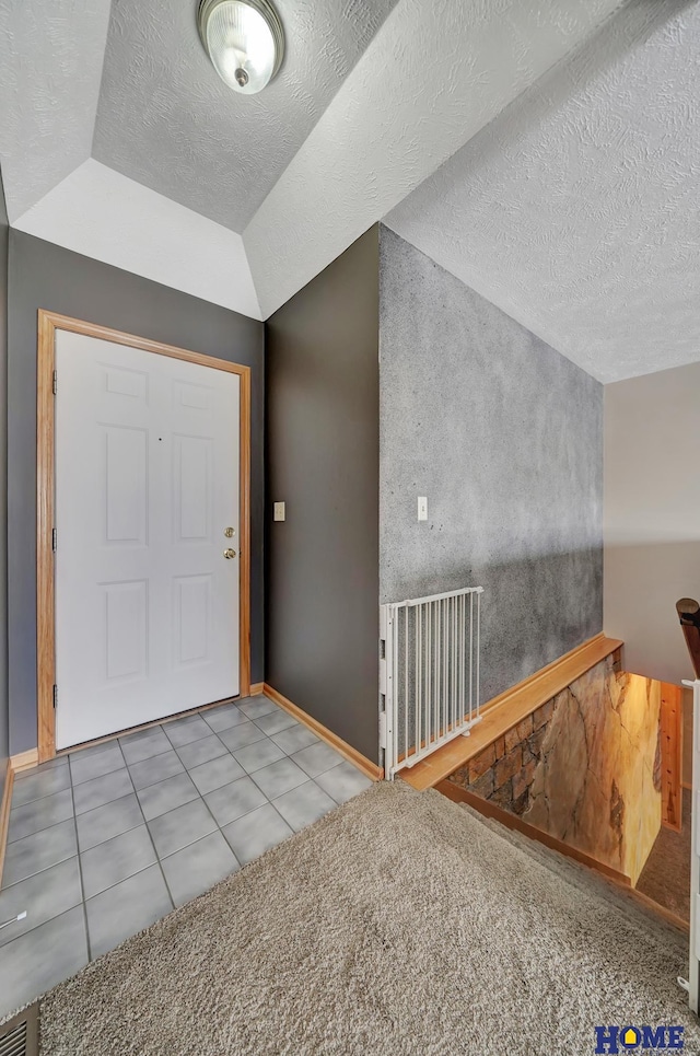 entryway with vaulted ceiling, tile patterned flooring, visible vents, and baseboards