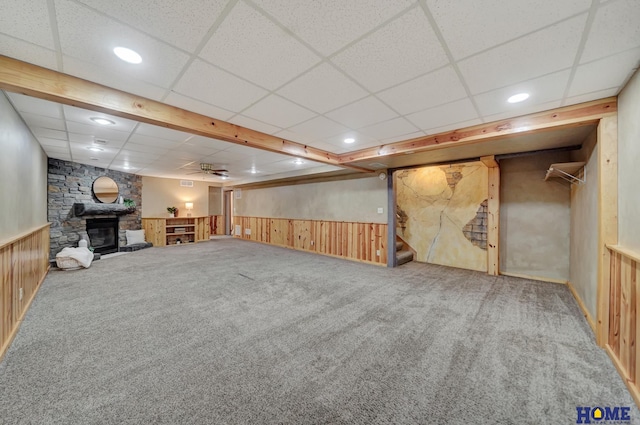 finished basement featuring carpet, a wainscoted wall, a fireplace, and stairs