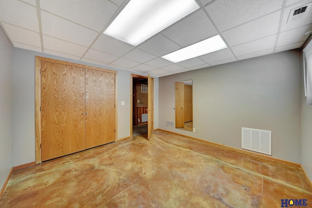 interior space with a paneled ceiling, baseboards, concrete floors, and visible vents