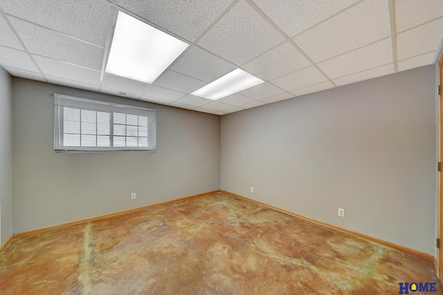 empty room featuring a drop ceiling, concrete floors, and baseboards