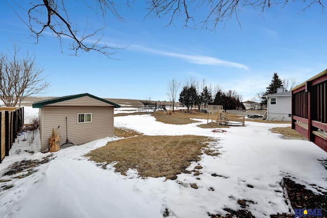 yard covered in snow featuring fence and an outbuilding