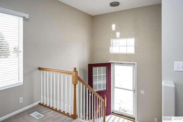 carpeted entryway with a healthy amount of sunlight, visible vents, and baseboards