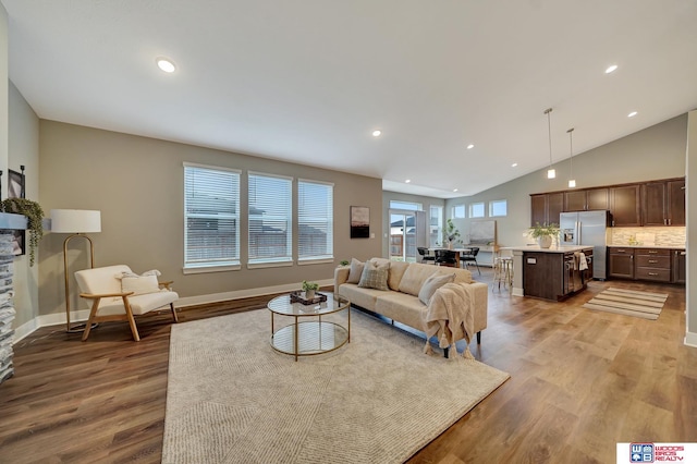 living area with high vaulted ceiling, recessed lighting, baseboards, and wood finished floors