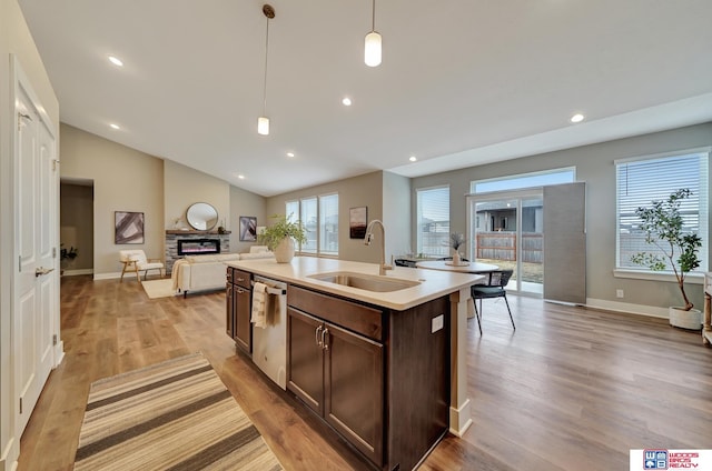 kitchen with a sink, light wood-style floors, open floor plan, dishwasher, and decorative light fixtures