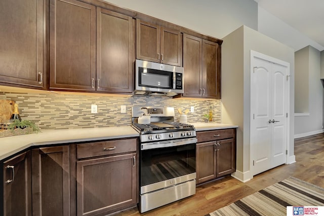 kitchen with light countertops, appliances with stainless steel finishes, wood finished floors, and tasteful backsplash