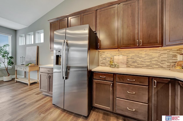 kitchen with light countertops, vaulted ceiling, light wood finished floors, and stainless steel fridge with ice dispenser