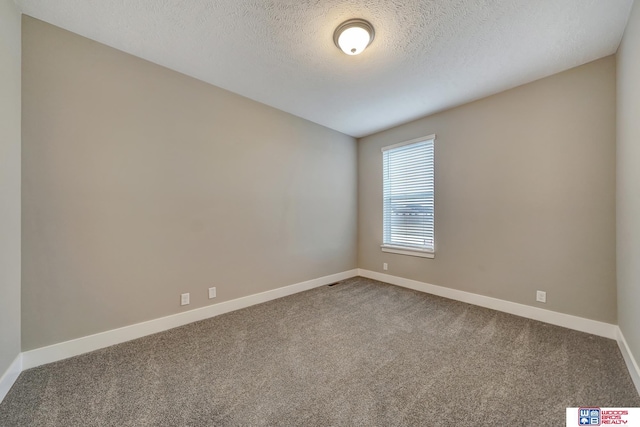 carpeted empty room featuring a textured ceiling and baseboards