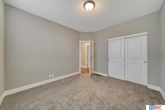 unfurnished bedroom featuring carpet floors, a closet, and baseboards