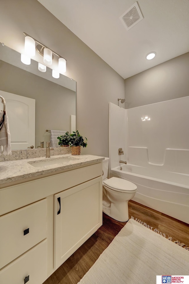 bathroom featuring visible vents, toilet, vanity, shower / tub combination, and wood finished floors