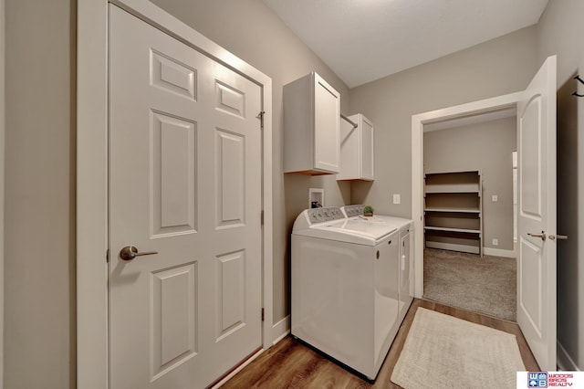 laundry room featuring washer and dryer, cabinet space, baseboards, and wood finished floors