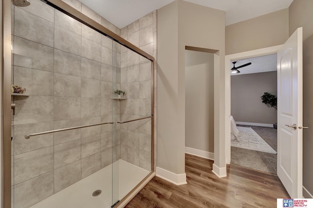 full bath with ceiling fan, a stall shower, wood finished floors, and baseboards