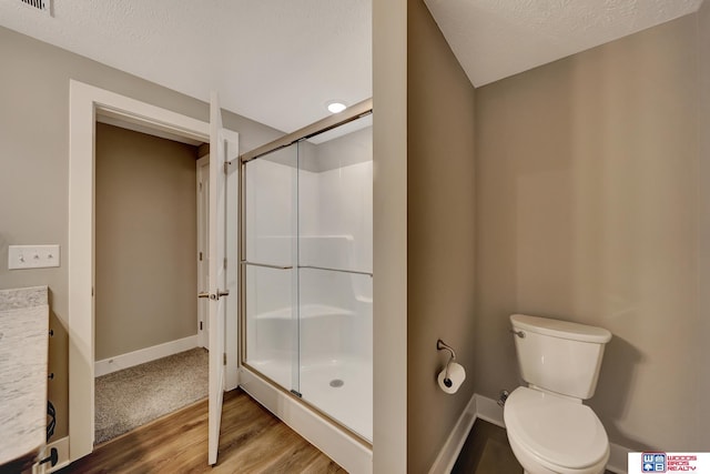 bathroom featuring a stall shower, wood finished floors, toilet, and baseboards