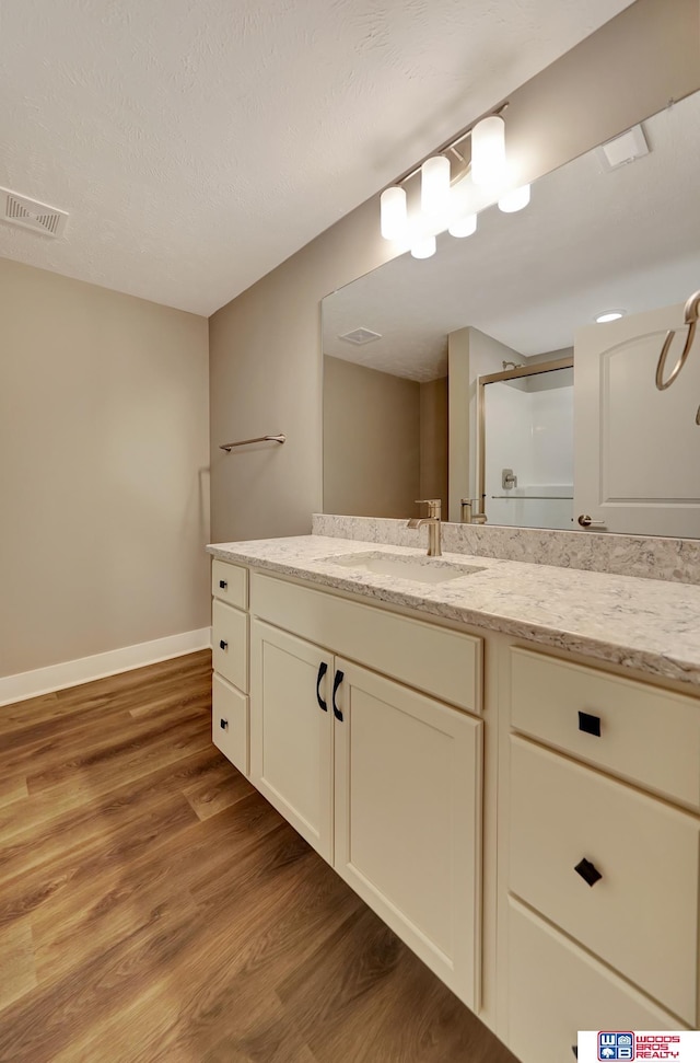 bathroom with visible vents, a shower stall, vanity, wood finished floors, and baseboards